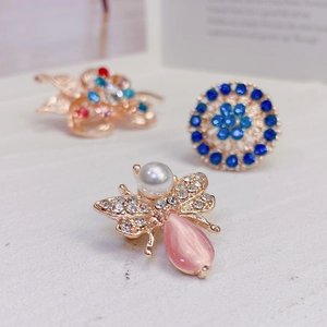 Macro detail of rhinestone bee brooch with pink gemstone and imitation pearl inlay