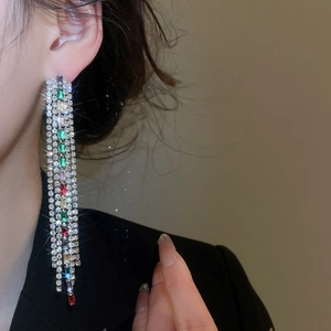 Close-up of elegant square zircon drop earrings with colorful rhinestone tassels worn on model