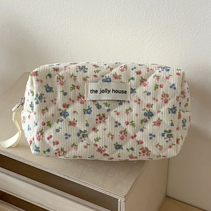 Detail of floral corduroy makeup bag featuring quilted fabric and brand label