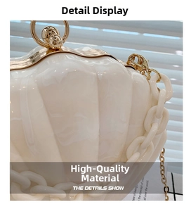 Detail view of cream shell-shaped acrylic bag with gold metal clasp and chunky chain strap