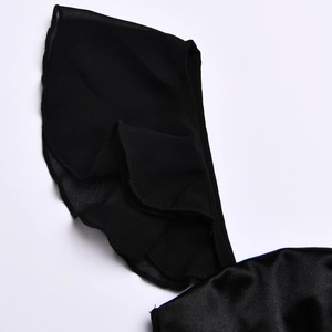 Dettaglio dei volant a strati in raso nero lucido sulla spalla dell'abito elegante