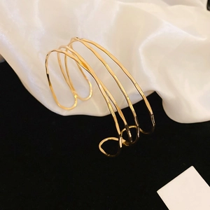 Detailed macro view of the irregular layered gold metal wrap bracelet on white silk fabric
