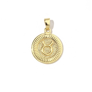Close-up of a 18k gold-plated Taurus zodiac charm with textured metal finish and cubic zirconia