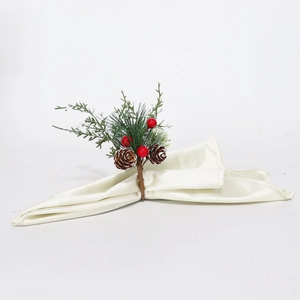 Détail du rond de serviette de Noël avec aiguilles de pin, baies rouges et pommes de pin