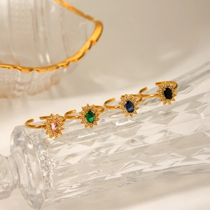 Close-up of four gold adjustable rings with sunburst zircon settings in multiple colors
