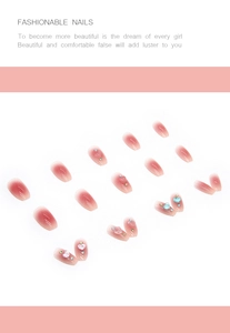 Detail of pink gradient press-on nails with 3D heart shapes and colorful rhinestones