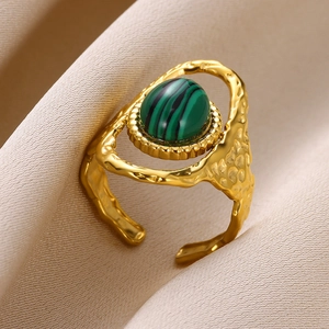 Détail d'une bague dorée en forme de soleil avec pierre turquoise verte et fini texturé