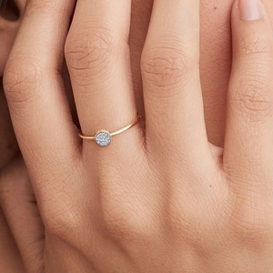 Macro detail of rose gold ring with blue pave-set birthstone crystals on a female hand