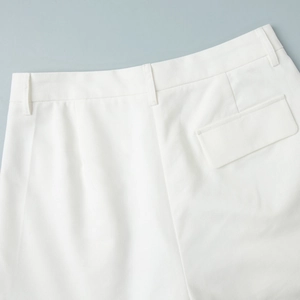 Detail of white trousers showing waist hook, belt loops, and rear flap pocket features