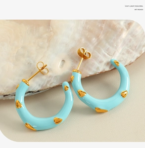 Detail of light blue enamel C-shaped earring with golden heart pattern on shell surface
