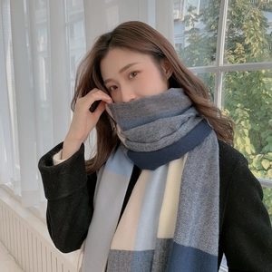 Detailed texture of thick cashmere-like scarf with blue, grey and beige plaid pattern