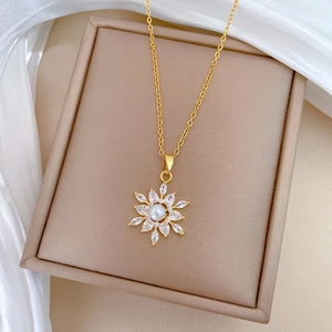 Close-up of golden snowflake pendant with zircon inlay and center pearl on a jewelry box
