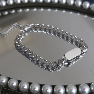 Silver Cuban link bracelet with oval tag on pearl mirrored tray in a punk hip hop style