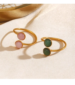 Detail of adjustable gold rings with pink and green semi-spherical stones on silk