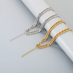 Detail of adjustable gold and silver curb chain necklaces on a minimalist gray stand