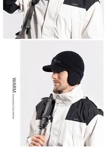 Detail of black thick knit beanie with ear flaps and visor for outdoor winter sports
