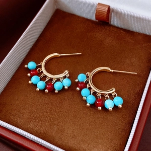 Detail view of 14K gold plated earrings with turquoise and red beads in a velvet jewelry box