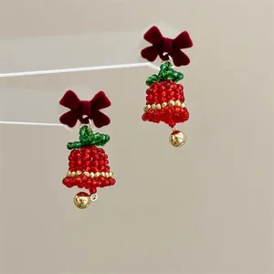 Close-up of handmade beaded Christmas bell earrings with a red velvet bow detail