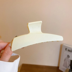 Detailaufnahme einer großen minimalistischen cremeweißen Haarklammer in der Hand