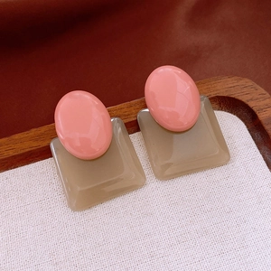 Detail of vintage gold-plated earrings with pink resin stone on wooden display tray