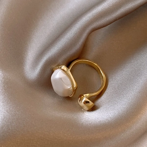 Detail of vintage irregular baroque pearl open ring on champagne silk background