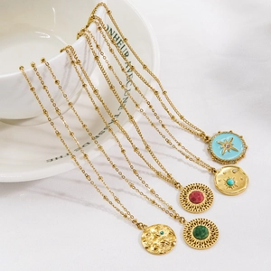 Set of five gold bohemian necklaces featuring colorful gemstone pendants on white ceramic