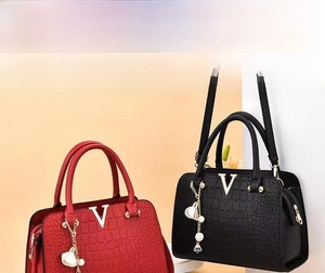 Detail of red and black crocodile embossed handbags with metallic V logo and floral charm