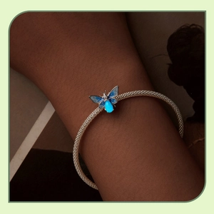 Luminous blue butterfly charm on 925 sterling silver mesh bracelet shown on wrist