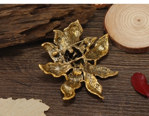 Detail view of the golden flower brooch back showing the secure safety pin fastener