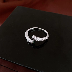 Vue macro d'une bague argentée avec zircons pavés et perles vertes sur socle noir