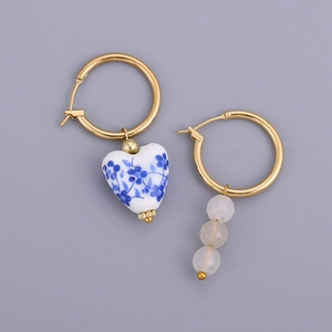 Detail of asymmetrical blue floral porcelain heart and beaded gold hoop earrings