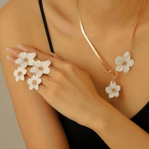 Elegant gold-tone necklace and ring set with white flower pendants worn by a model