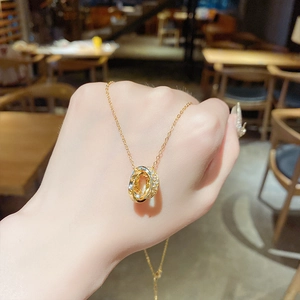 Close-up of interlocking gold rings with sparkling zircon pavé on a fine chain