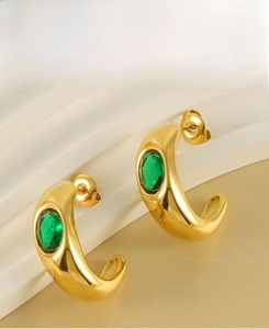 Detail of C-shaped gold-plated earrings with emerald green oval-cut center stones