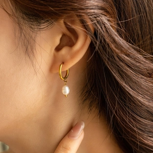 Minimalist gold hoop earring with natural pearl pendant on model side profile view