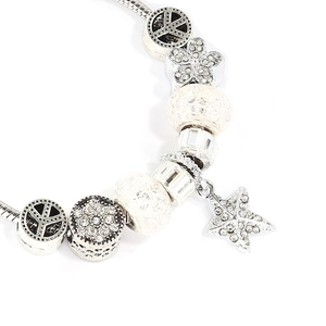 Detail of silver snake chain bracelet with starfish pendant and floral beads