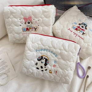 Detail of white heart-quilted makeup pouch featuring cute cartoon puppy embroidery