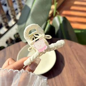 Detail of cream fabric wrapped hair claw clip with pink cartoon cat on wooden background