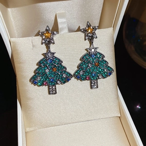Vue macro de boucles d'oreilles sapin de Noël avec cristaux multicolores sur velours beige