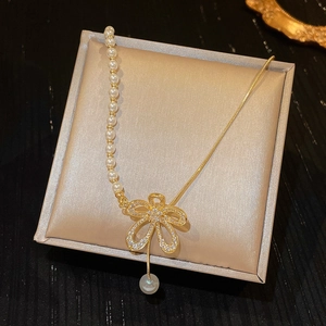 Close-up of baroque pearl necklace with gold flower pendant in a beige gift box