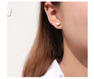Close-up of polished gold heart stud earrings worn for an elegant minimalist look