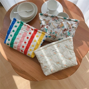 Detailed view of three quilted floral bear pattern makeup bags on a wooden table