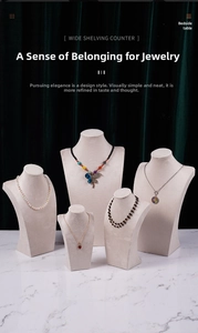 Detail view of velvet beige necklace display busts in various sizes on marble surface