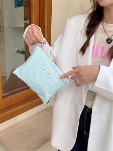 Light blue fabric makeup bag with pink zipper and circle puller held by a model