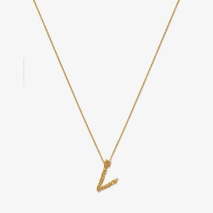 Macro detail of a textured gold initial L pendant with shimmering diamond accents