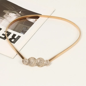 Detail view of golden elastic metal waist chain with vintage textured round buckle