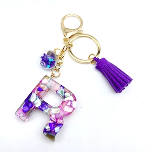Letter R resin keychain with purple tassel and shell fragments in gold metal finish