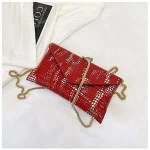 Detail of red crocodile texture envelope clutch bag with gold chain strap on flat lay