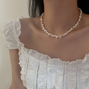 Close-up of baroque freshwater pearl necklace worn by a model with elegant white ruffles