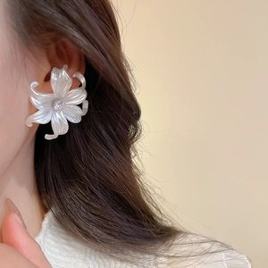 Close-up of elegant large white flower earrings with zircon center on model